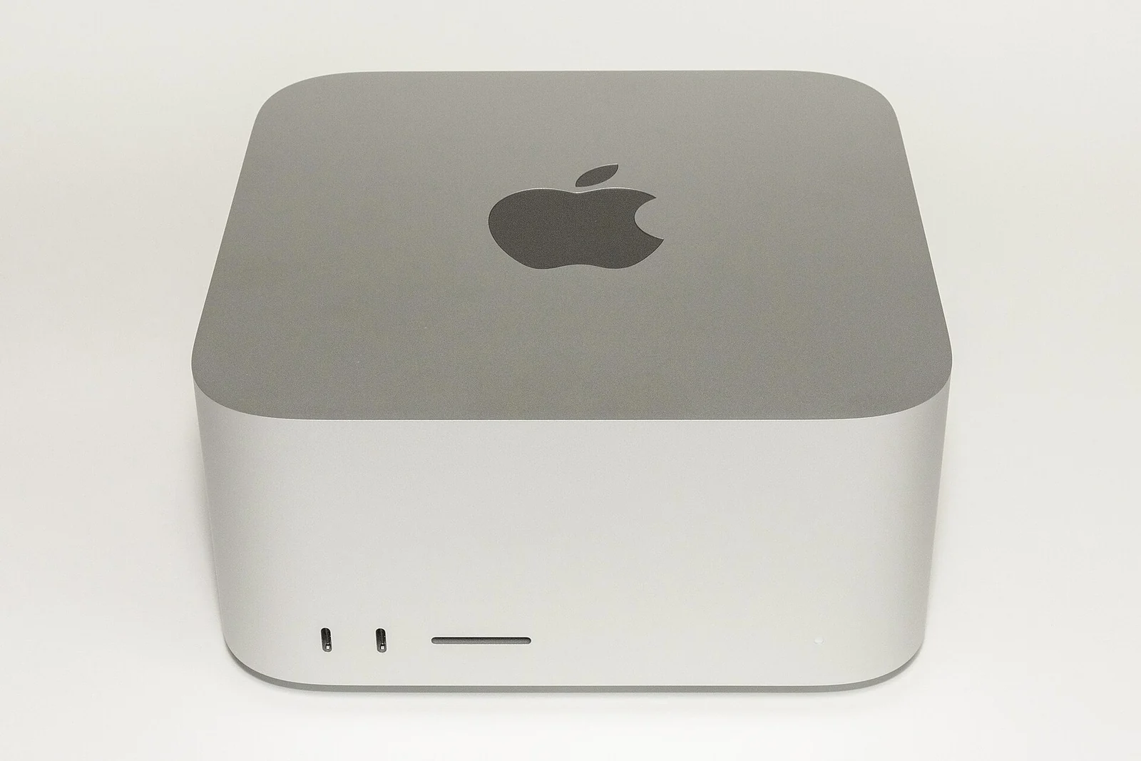 Серебристый компьютер Mac Studio 2022 года, вид спереди и сверху.